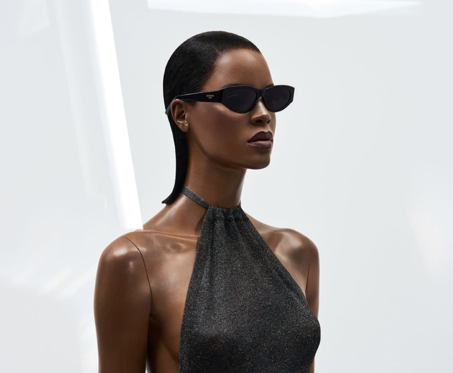 Person wearing black sunglasses and a sleeveless halter top against a light background.