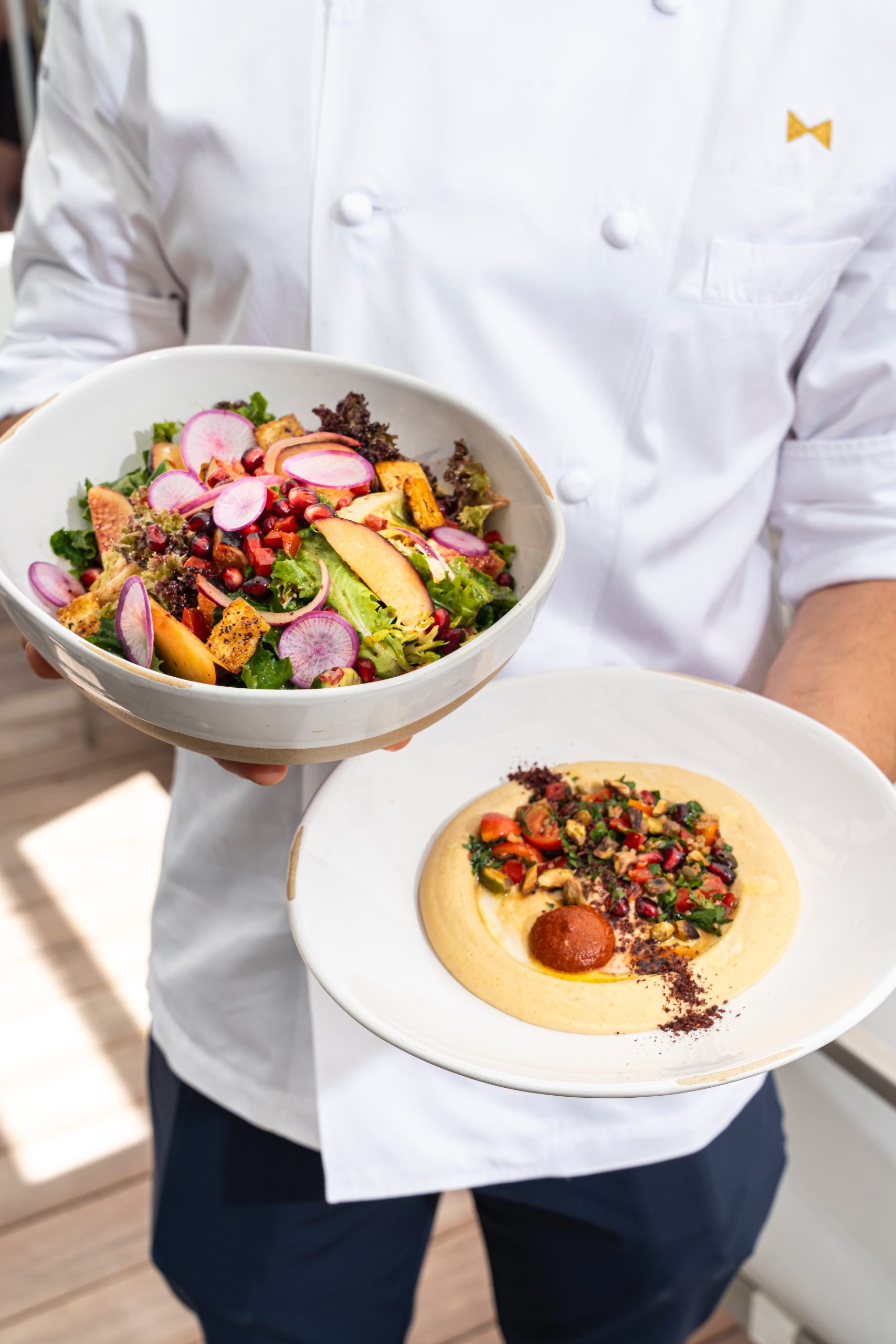 Chef holding two dishes at La Côte