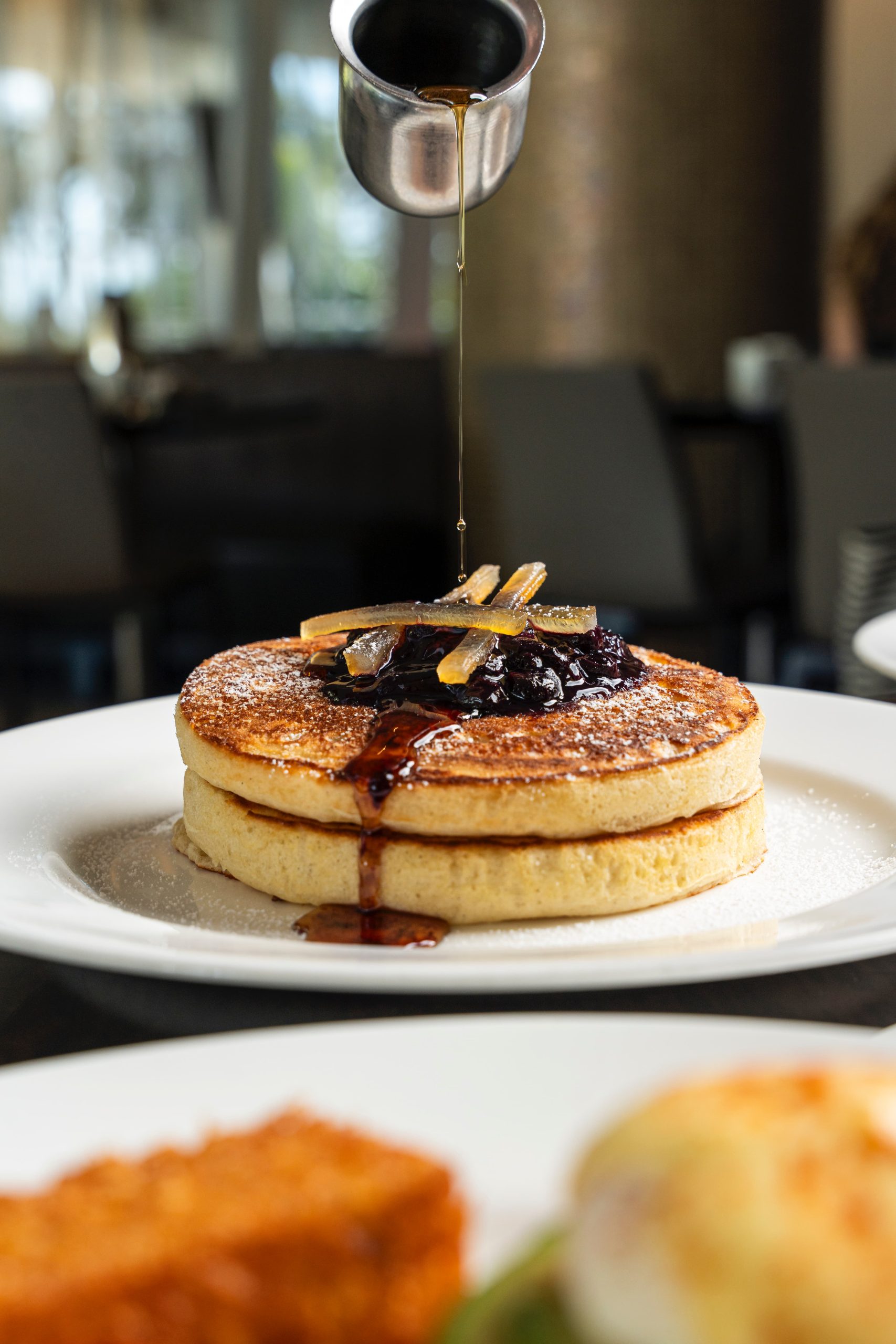 maple syrup being poured over pancakes at Vida restaurant
